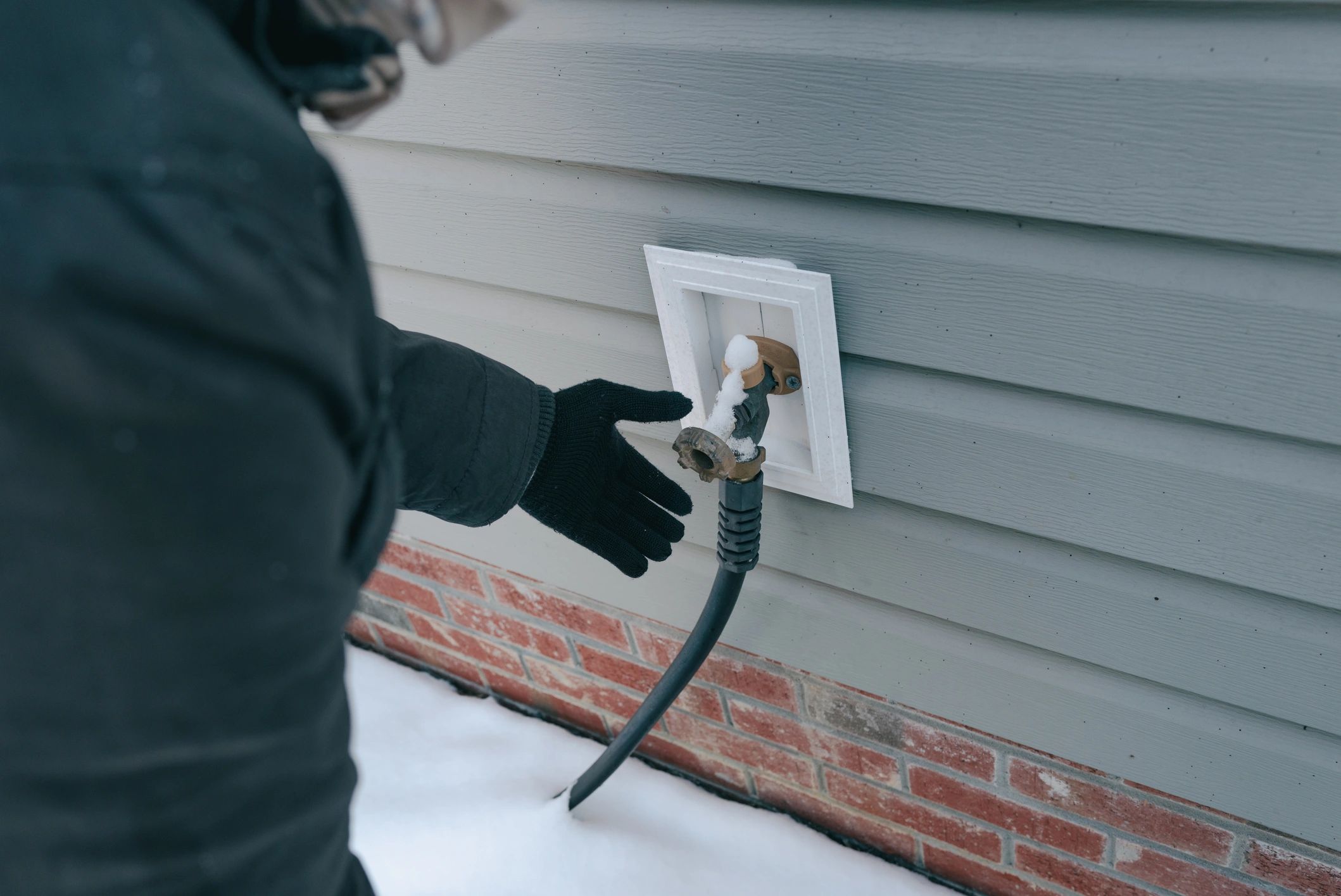 Outdoor water faucet being checked during cold weather