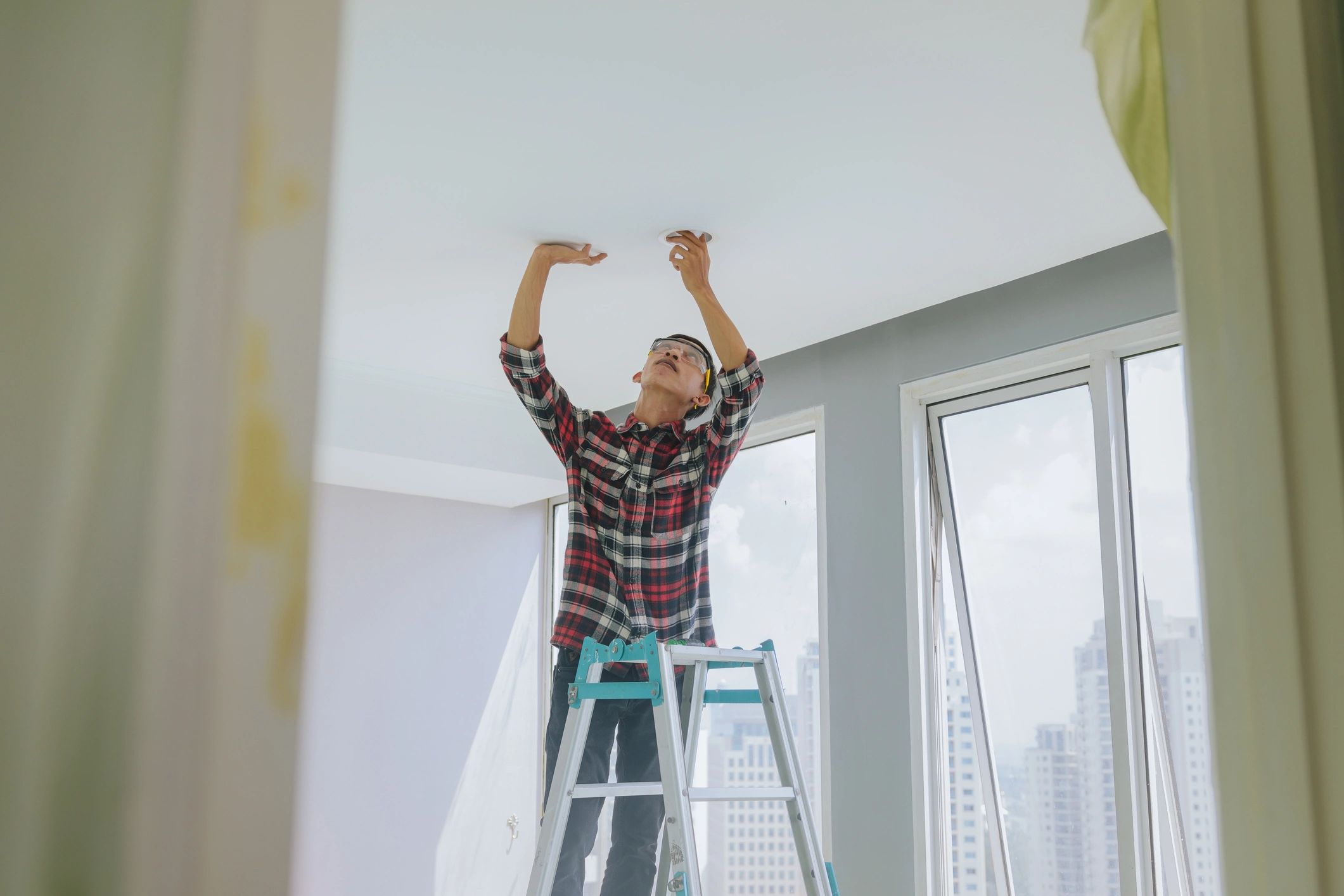 Technician installing an LED ceiling light in a modern home